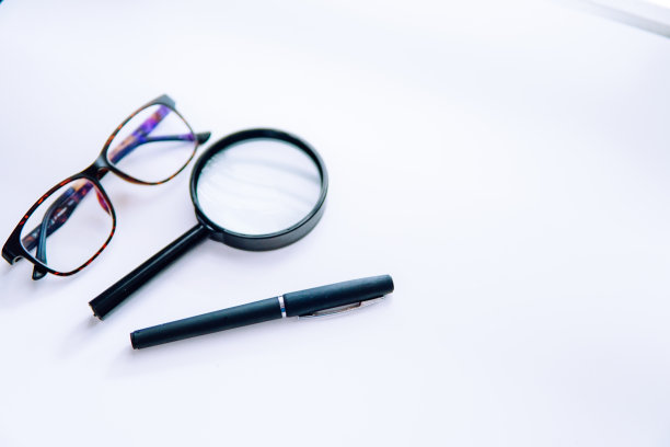 黑色钢笔，放大镜和玻璃上的白色背景。企业财务的概念。本空间图片下载
