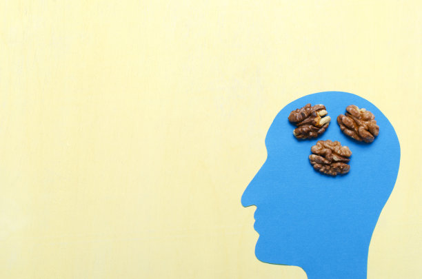 俯视图的蓝色头部剪影和剥皮核桃在黄色的背景。空的空间。食物对大脑图片下载