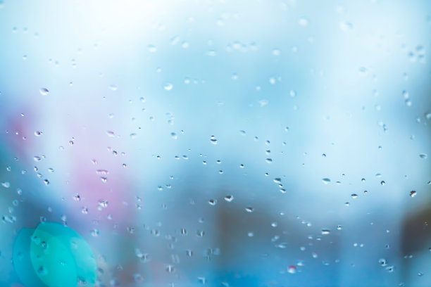 在潮湿寒冷的天气里，蓝色照明的窗户玻璃上有雨滴纹理的抽象背景图片下载