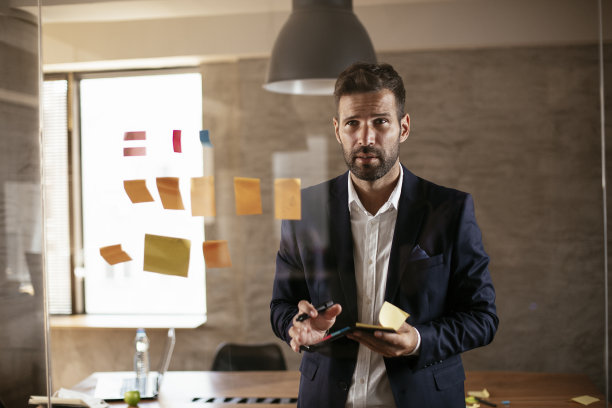 会议室的商人在玻璃墙上使用便利贴。图片下载