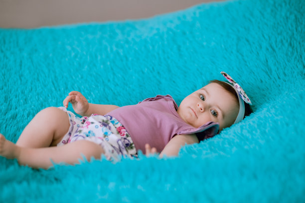 六个月大的婴儿躺在床上，仔细地看着镜头图片下载