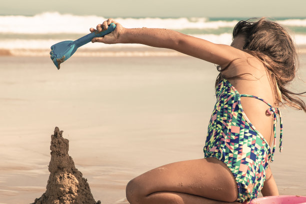 可爱的小女孩用塑料铲搭沙堡图片下载