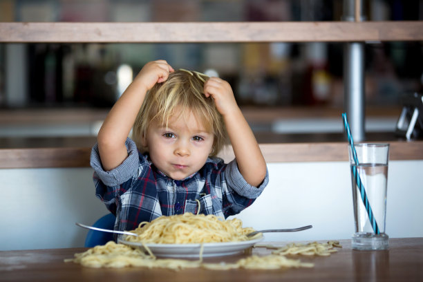 小男孩，蹒跚学步的孩子，午餐吃意大利面，喂泰迪熊朋友图片下载