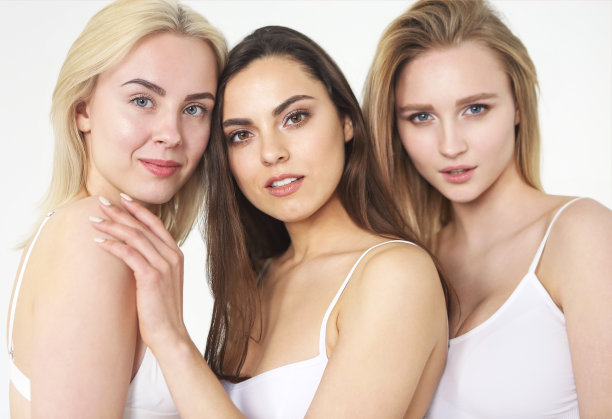 一群快乐的不同女人在白色的背景下拥抱。图片下载