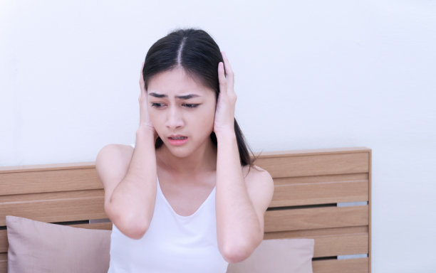 迷人的年轻女子在卧室里捂住她的烦恼耳朵。图片下载