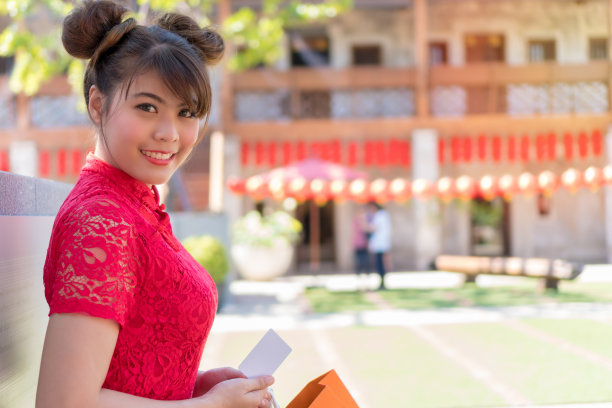 迷人的女人穿着旗袍红裙看着镜头在中国氛围的背景与复制空间。人、美和民族观念。图片下载