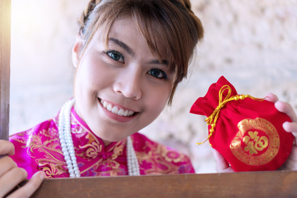 春节快乐的概念。喜气洋洋的年轻女子穿着旗袍，手里拿着红色的昂袍，里面装着家人给她的钱，表示幸运和繁荣。在中文里，红包的意思是好运图片下载