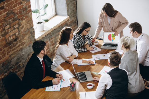 女演讲者在讲习班大厅演讲。观众或会议厅。参与者，坐在桌子旁倾听的同事。图片下载