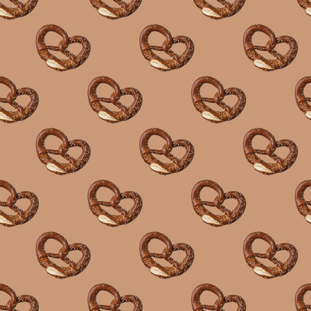 新鲜烘焙椒盐卷饼无缝模式上的棕色背景。概念的食物图片下载