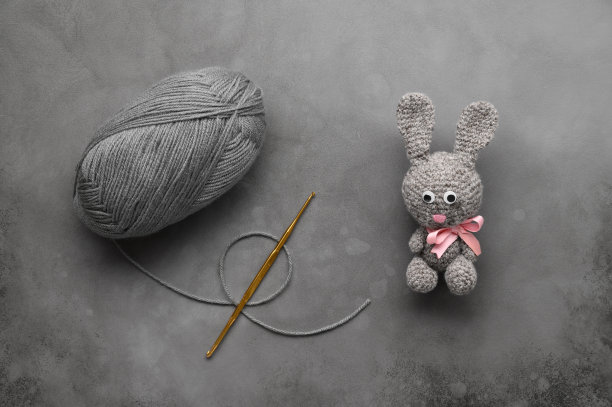 复活节手工DIY。手工钩针兔子玩具，毛线球，针织针在深灰色的背景。俯视视图，文字空间，平放图片下载