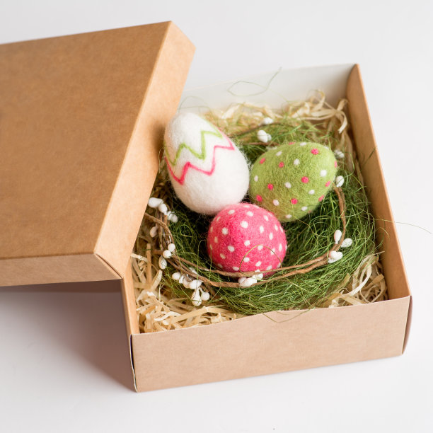 在白色的背景下，用羊毛制成的复活节彩蛋放在礼品盒里。复活节的礼物包装图片下载