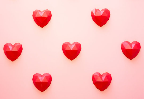 情人节的节日背景，红色的多边形纸心形的奶油背景。爱的概念。平原。简约的风格。图片下载