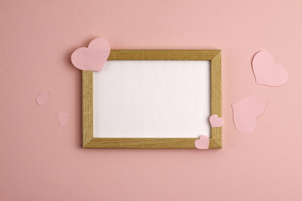 情人节当天，粉色背景的纸心和木框附近图片下载