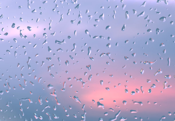 水滴在透明的玻璃上。雨点落在窗户上，映衬着暴风雨般的日落天空，深蓝色的天空中有红色的缝隙。雷雨后的心情。抽象背景与水滴图片下载