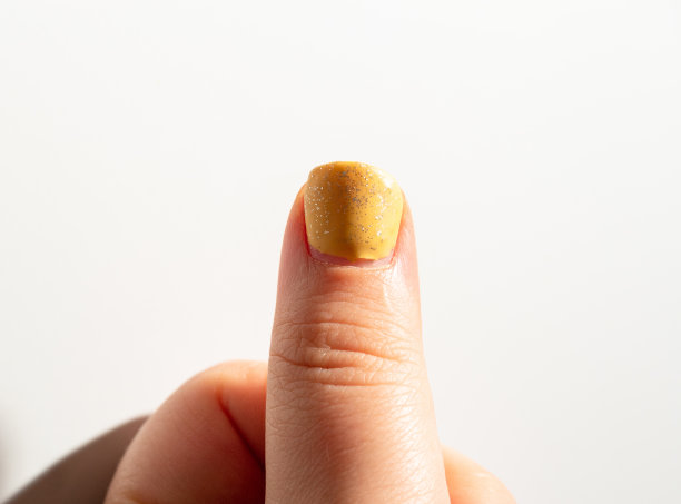 大脚趾有半英寸的涂胶抛光黄色。有选择性的重点。特写镜头。白色背景。图片下载