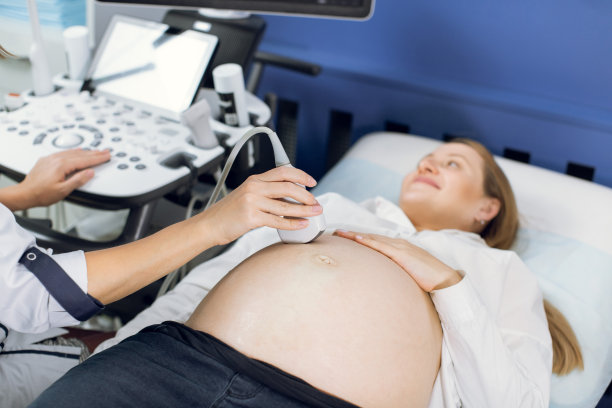 特写医生的双手，使用现代超声波设备对孕妇的腹部进行筛查，并按下专用电脑的按钮图片下载