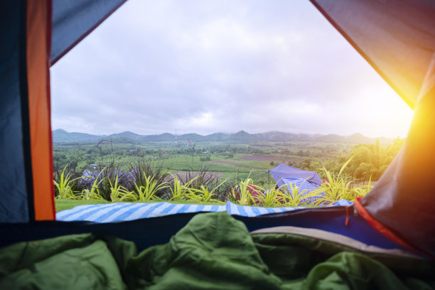 从帆布帐篷望向绿油油的草地，有树，有山。观点图片下载