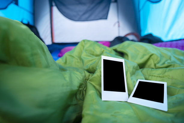 在帐篷里的睡袋上放了两张宝丽来相机，用来记录这次旅行的记忆图片下载