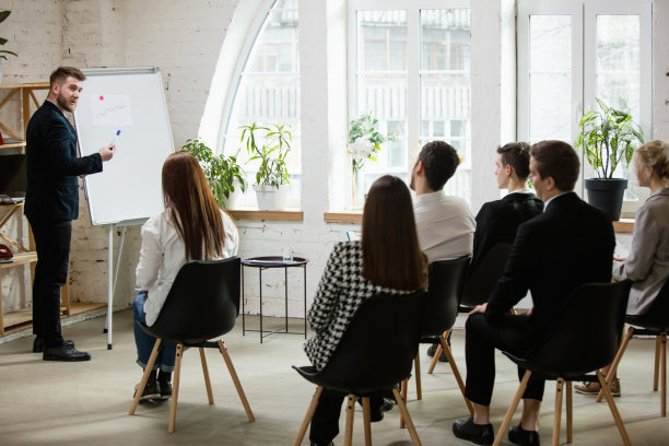 男演讲人在车间大厅演讲。观众或会议厅。未被认出的参与者的后视图。图片下载