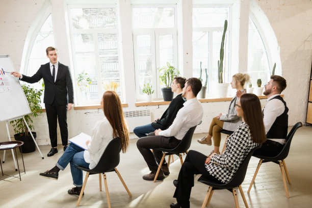男演讲人在车间大厅演讲。观众或会议厅。未被认出的参与者的后视图。图片下载