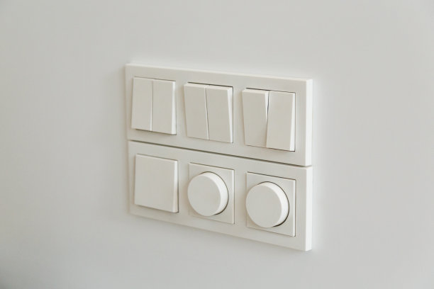 灯光开关，白色塑料机械开关安装在灰色的墙上。图片下载