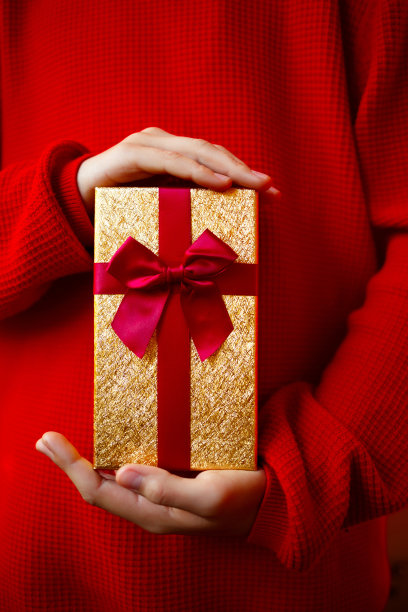 美丽明亮的礼物在一个孩子的手中在一个红色的背景图片下载