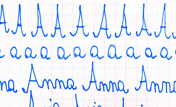 歪歪扭扭的字母由孩子写，孩子练习书法，学习写简单的字。字母A，姓名安娜初学教育理念，蓝墨水笔方格笔记本特写图片下载
