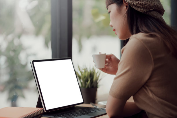 模型。这是一幅亚洲女性在咖啡店里喝着咖啡，在笔记本电脑上工作，屏幕是空白的。图片下载