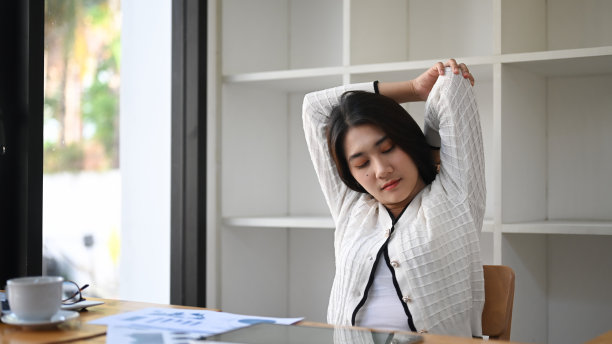 女商人在舒适的办公椅上放松，伸展双臂。图片下载