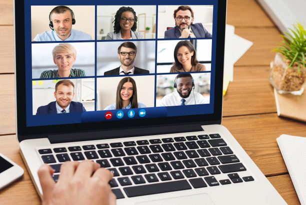 用笔记本电脑与坐在室内电脑前的同事交流的女人图片下载