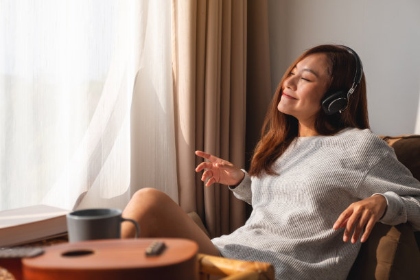一位年轻美丽的亚洲女子喜欢在家里用耳机听音乐图片下载