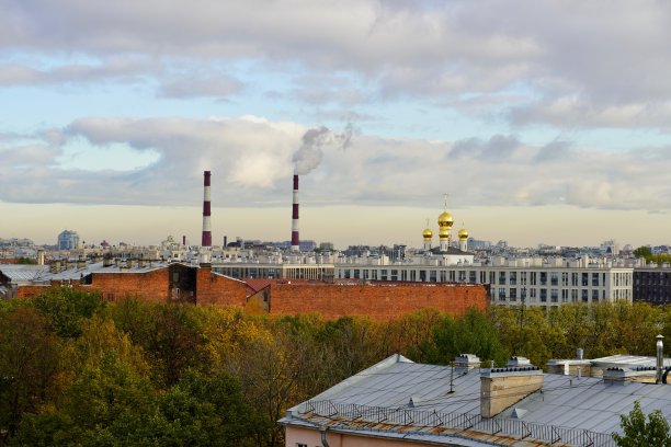 一个工业城市景观和一个有烟筒的钢铁厂和一个多云的天空作为背景。城市景观的对比——植物的管道和教堂的圆顶映衬着美丽的天空。这张照片拍摄于俄罗斯圣彼得堡图片下载