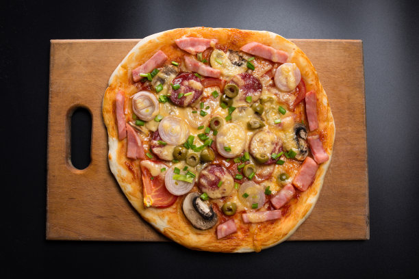 蘑菇香肠披萨。新鲜的披萨放在黑色木板上图片下载