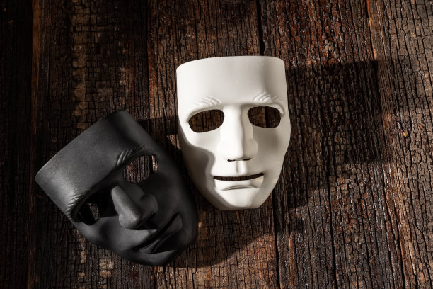 黑色和白色的面具在木制的复古背景上，象征着匿名和戏剧。用阴影特写，复制空间图片下载
