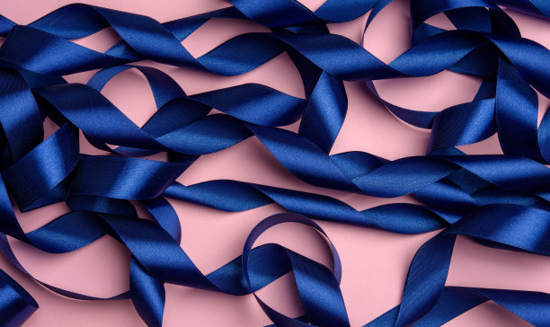 卷曲的蓝色丝带在粉红色的背景，节日的背景图片下载