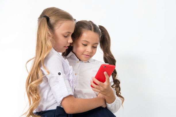 教育应用程序。在线娱乐的概念。可爱的女学生们用智能手机查看社交网络。发送消息的朋友。在线交流信息。浏览有趣的网站图片下载