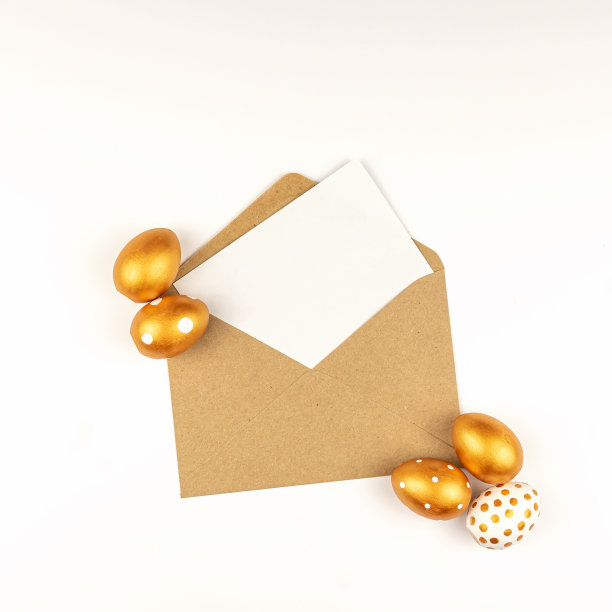 复活节的节日装饰。顶部的复活节彩蛋与金色油漆和空模型卡在一个牛皮纸信封。各个点的设计。白色背景。图片下载