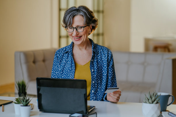 高级快乐时尚的女人做网上购物使用笔记本电脑与信用卡图片下载