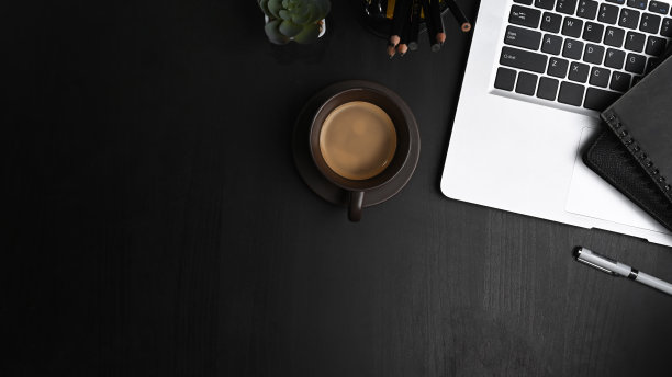 头顶拍摄的当代工作空间与笔记本电脑，咖啡杯，笔记本和拷贝空间在黑色的桌子上。图片下载