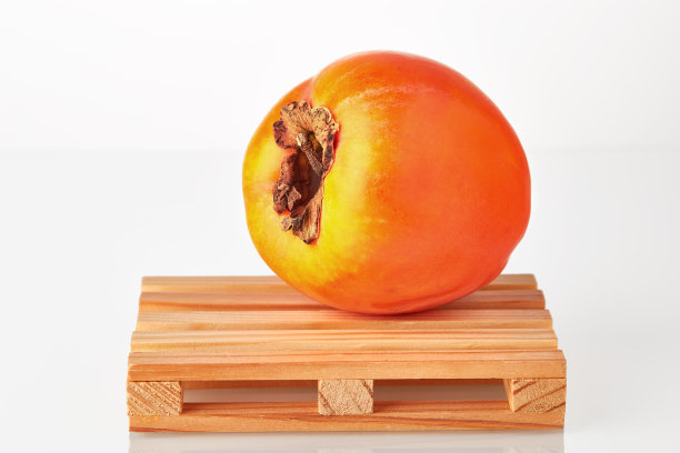 新鲜的柿子在物流托盘上等待运输到目的地，隔离在白色的背景。水果出口或进口。图片下载