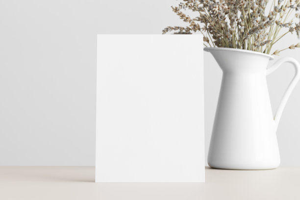 白色请柬模型，米色桌子上放着干薰衣草。5x7的比例，类似于A6, A5。图片下载