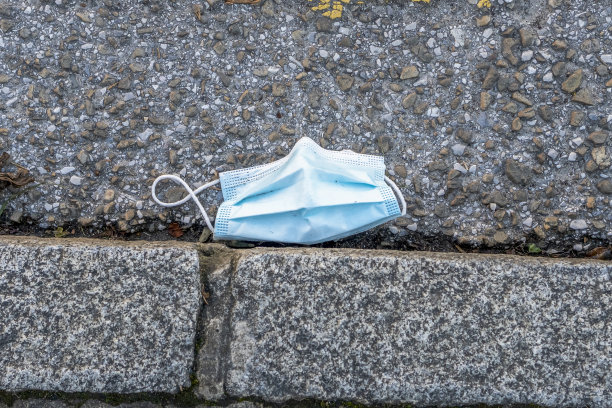 一个用过的外科口罩扔在柏油路上图片下载