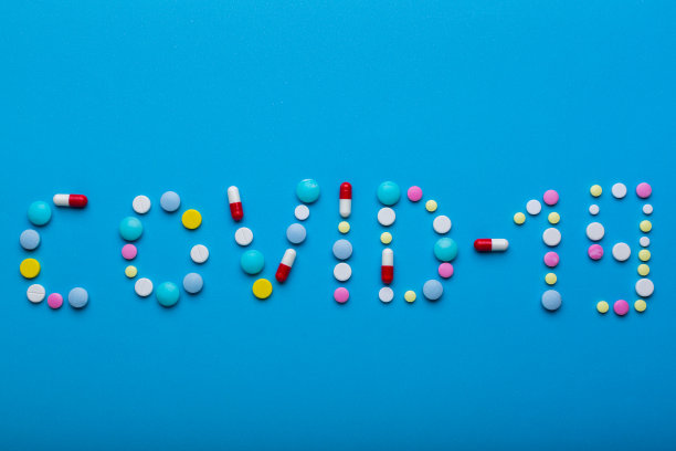 Word covid19在蓝色背景上写了五颜六色的药片，并留出了文本空间图片下载