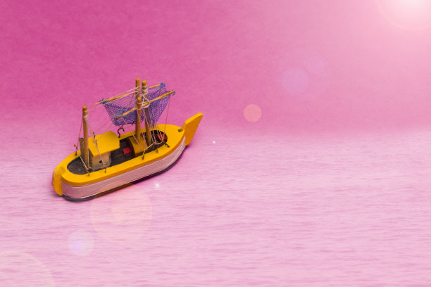 旅行的想法和概念。模型的旧帆船放置在粉红色的背景和太阳耀斑添加。水平的形象图片下载