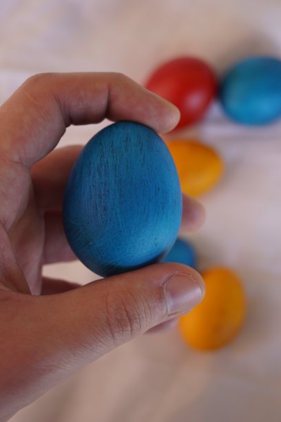 拿着蓝色的复活节彩蛋，彩色的彩蛋在桌子上的背景-库存照片图片下载