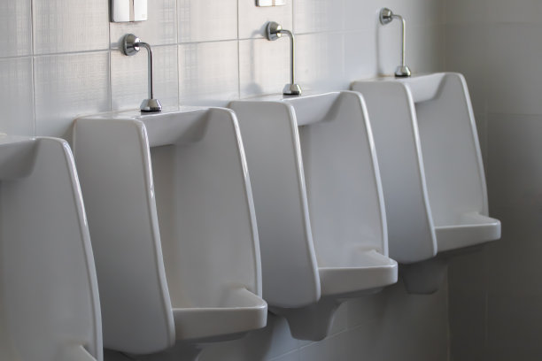 男性公共厕所的白色陶瓷小便池。图片下载