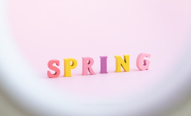 “春天”这个词用木制的彩色字母在粉色的背景上图片下载