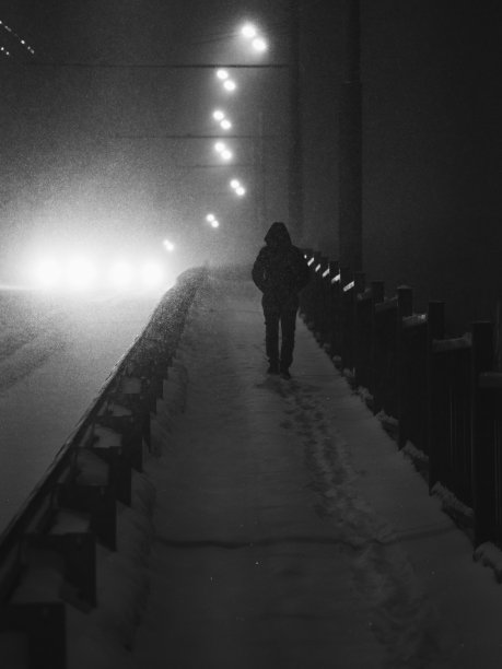 一个人的剪影走过一个大雪覆盖的城市，黑白照片图片下载