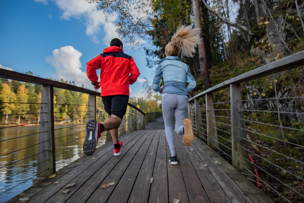 两个人在公园里从桥上跑过的后视图。图片下载