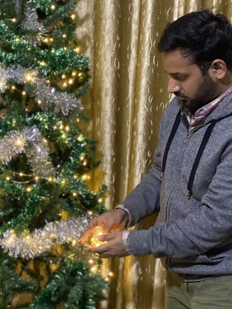 印度人在人造圣诞树上放置装饰品和装饰品，包括银箔、小装饰品和串线仙女灯图片下载